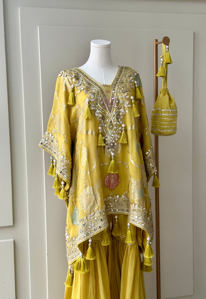 yellow embroidered kurta set with intricate mirror work, sequins, and tassel details, paired with flowy sharara pants and a matching embellished potli bag. Perfect for festive occasions and weddings